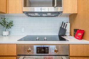 una cocina con estufa y microondas en Sky Ala Moana 2908 condo, en Honolulu 23 fotos más