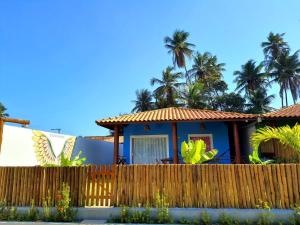ein Haus mit Palmen hinter einem Zaun in der Unterkunft Chalés Cantinho Da Mary in São Miguel dos Milagres