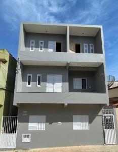 un edificio gris con puertas y ventanas blancas en Pousada Lavínia, en São Thomé das Letras