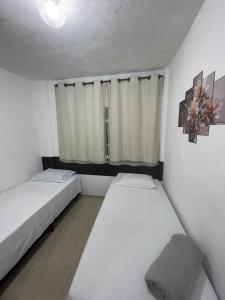 a small room with two beds and a window at Pousada Lavínia in São Thomé das Letras