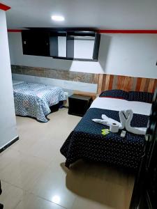a bedroom with two beds and a tv on the wall at Hotel Villa Real in Bogotá