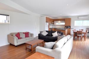 a living room with two couches and a kitchen at Flying Colours Free Wifi in Inverloch