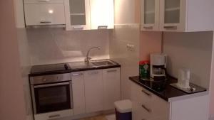 eine kleine Küche mit weißen Schränken und einem Waschbecken in der Unterkunft Apartments by the sea Biograd na Moru, Biograd - 21597 in Biograd na Moru