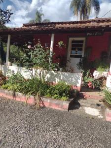 una casa roja con una puerta blanca y algunas plantas en Chácara pão de açúcar, en Bueno Brandão