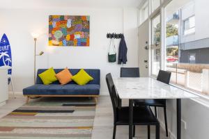 une salle à manger avec un canapé bleu et une table dans l'établissement 2BR Bondi Beauty - Elena by the Sea, à Sydney