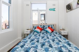 - une chambre avec un lit doté d'oreillers bleus et rouges dans l'établissement 2BR Bondi Beauty - Elena by the Sea, à Sydney