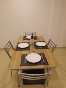 una mesa de madera con platos blancos y una botella de vino en Departamento a estrenar GALO VII en San Bernardo