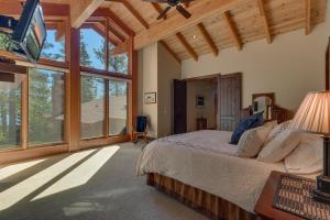 a bedroom with a bed and a large window at Gray Bear Lake View Estate - Stunning Cabin w 4 Master Suites, Private Hot Tub! in Carnelian Bay