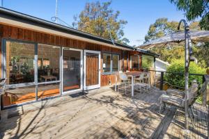 a house with a deck with a table and chairs at Coastal Charm in Lorne