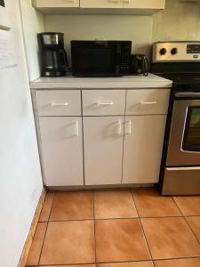 a kitchen with white cabinets and a microwave at Beds & Sheets Little Havana in Miami