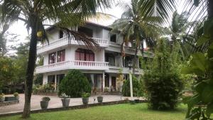 un gran edificio blanco con árboles delante de él en Hotel Lagoon Paradise, en Negombo