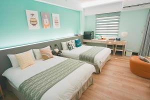 a hotel room with two beds and a desk at Green Stay in Hualien City