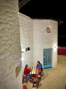 zwei Personen sitzen an einem Tisch in einem Gebäude in der Unterkunft Huanchaco Domes in Huanchaco