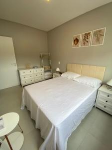 Un dormitorio con una gran cama blanca y una mesa en Paraíso em Palmas com Piscina - 3 min do mar a pé!, en Governador Celso Ramos