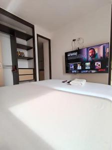 a bedroom with a white bed with a tv on the wall at Alex & Kamilo in Bucaramanga