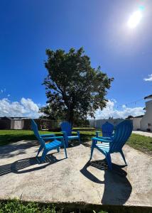 three blue chairs and a table and a tree at Villa Alborada in Arecibo