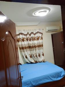 - une chambre avec un lit bleu et un rideau dans l'établissement HeliopolisStar, au Caire