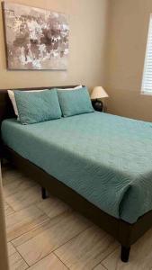 a bedroom with a bed with green sheets and pillows at Paradise Oasis! Waterfall pool & spa in Lake Havasu City