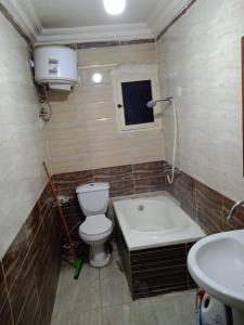La salle de bains est pourvue de toilettes, d'une baignoire et d'un lavabo. dans l'établissement HeliopolisStar, au Caire