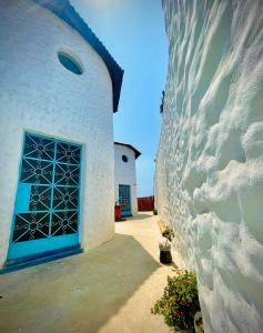- un bâtiment blanc avec une porte bleue et un mur dans l'établissement Huanchaco Domes, à Huanchaco