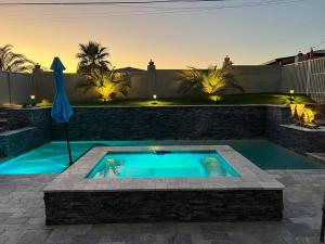 a swimming pool in a backyard with an umbrella at Paradise Oasis! Waterfall pool & spa in Lake Havasu City