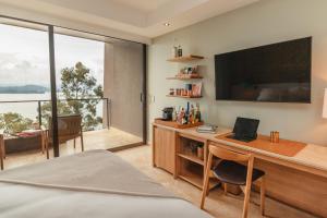 a bedroom with a desk with a laptop and a large window at The Brown, Guatape in Guatapé