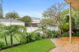 a garden with palm trees and a white fence at Blissful Beachfront Pad - Pet Friendly - Direct Beach Access in Blue Bay 