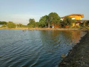 una gran masa de agua con una casa en el fondo en The Orange House Thailand - Baan P'Nae Homestay en Ban Khlong Bang Khrok