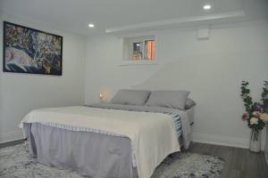 um quarto branco com uma cama e um vaso de flores em Entire Basement - 5 Guests 2 Bedrooms 3 Beds em Toronto