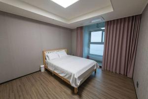 um quarto com uma cama num quarto com uma janela em Kangdong K Residence em Ulsan
