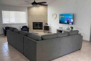 a living room with a large couch and a flat screen tv at Spacious Getaway! Pool, Spa, Sleeps 9 in Lake Havasu City