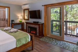 een slaapkamer met een open haard, een bed en een televisie bij Sheridan House Inn- Adult Only Accommodation in Williams