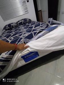 een persoon die een bed opmaakt met een blauw en wit dekbed bij Tranquilo y cómodo apartamento in Medellín
