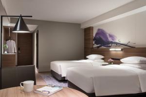 守山市にある琵琶湖マリオットホテルのベッド3台とテーブルが備わるホテルルームです。