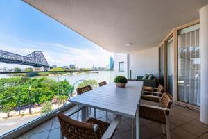 een balkon met een tafel en stoelen en uitzicht op een rivier bij Story Bridge view apartment with parking and pool in Brisbane