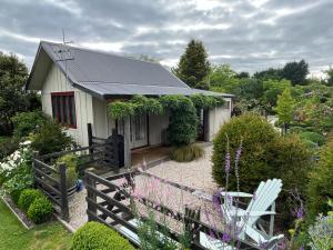 uma pequena casa com uma cerca e um jardim em Tasman Village Cottage em Tasman