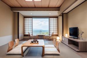 Lake Biwa Marriott Hotel في Moriyama: غرفة معيشة فيها تلفزيون وطاولة وكراسي