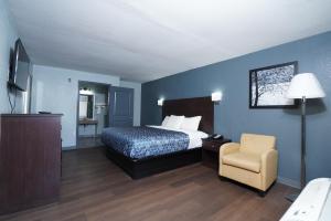 a hotel room with a bed and a chair at Red Carpet Inn & Suites in Newnan +21 photos