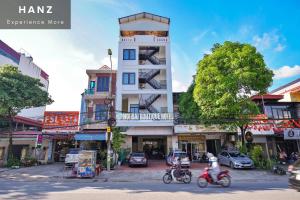 two people riding motorcycles on a street in front of a building at HANZ Noi Bai Airport Hotel in Hanoi