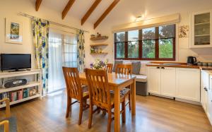 uma cozinha e sala de jantar com uma mesa de madeira e cadeiras em Tasman Village Cottage em Tasman