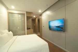 um quarto com uma cama branca e uma televisão de ecrã plano em Elite Hotel em Ha Long