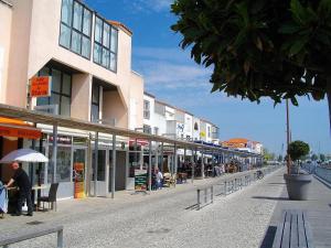 a street with buildings and people sitting on benches at T2 Rénové avec Parking, près Port de Plaisance et Plage - Les Sables-d'Olonne - FR-1-92-929 in La Chaume