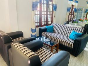 a living room with three couches and a table at Lavendra Guset House in Adams Peak