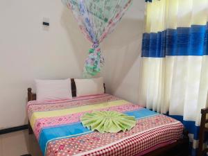 a small bedroom with a bed with a curtain at Lavendra Guset House in Adams Peak