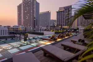 una piscina en la azotea con sillas y mesas sobre el perfil urbano en Payaa Hotel, en Pattaya central