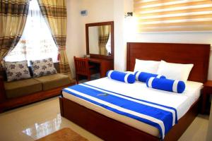 een slaapkamer met een bed met blauwe en witte kussens bij Nature First Hotel in Nuwara Eliya