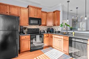 a kitchen with wooden cabinets and black appliances at Whitehall Dawg Den - Right by North Oconee River! in Athens