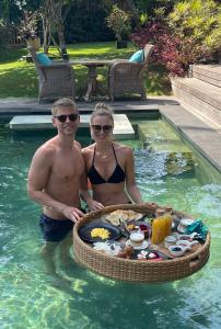 a man and woman standing in a swimming pool with a tray of food at Louka Beach Bali in Tianyar