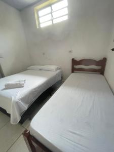 Duas camas num pequeno quarto com uma janela em 02 Doutor hostel 800 mts da praia no Guarujá