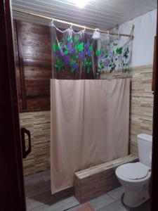 a bathroom with a toilet and a shower curtain with flowers at Chalé Ebenézer in Eldorado